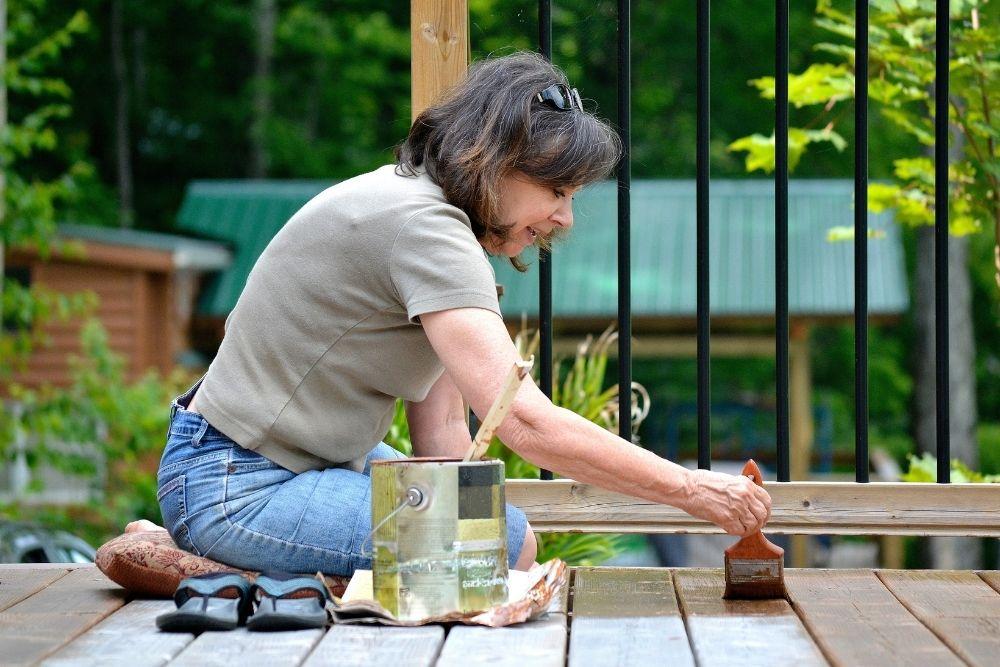 Woman applying paint on the deck