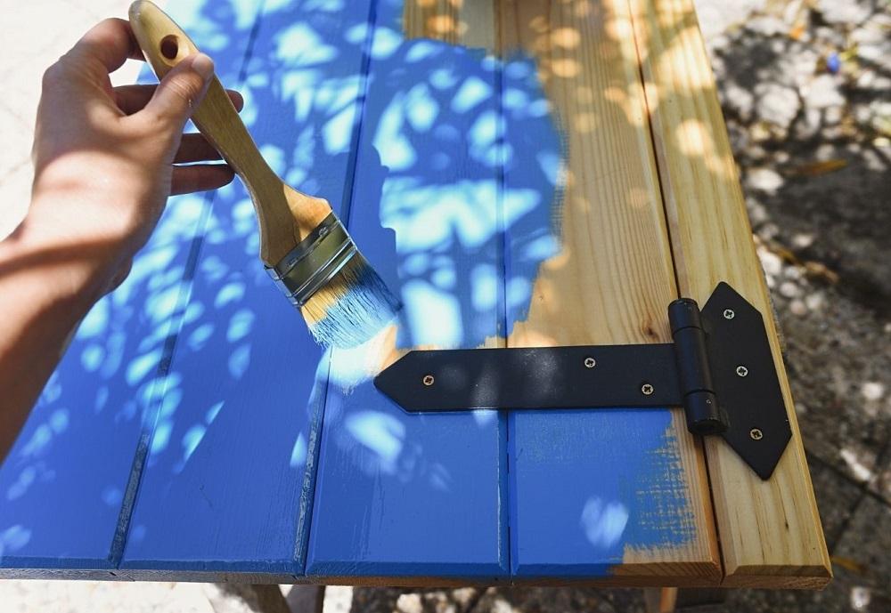  FREE Hand with paint brush painting a pine wood shutter in blue